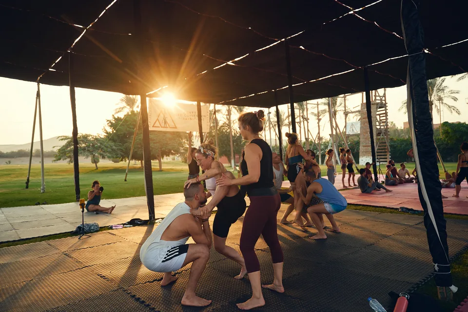 Participants practising acro on the shaded training floor at sunset