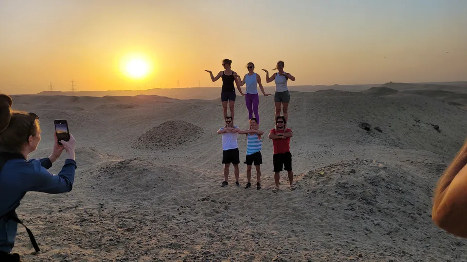 Participants making two-high acro poses in the desert at sunset